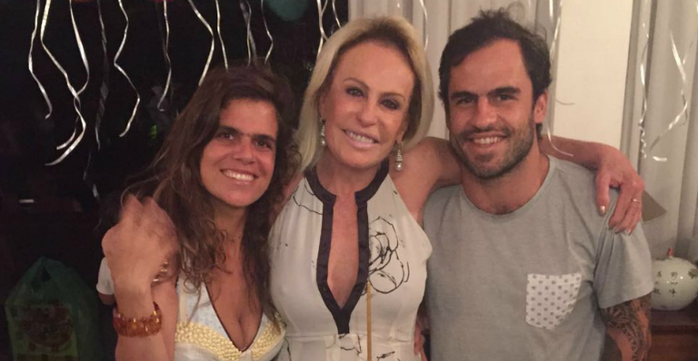 Ladeada pelos herdeiros, Mariana e Pedro, a apresentadora é tomada pela emoção.